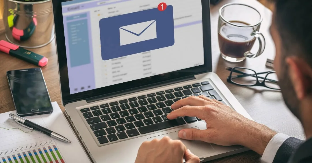 Man typing on a laptop with a new email notification on screen